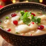 A bowl of roasted red pepper Gouda soup with cream and basil garnish.